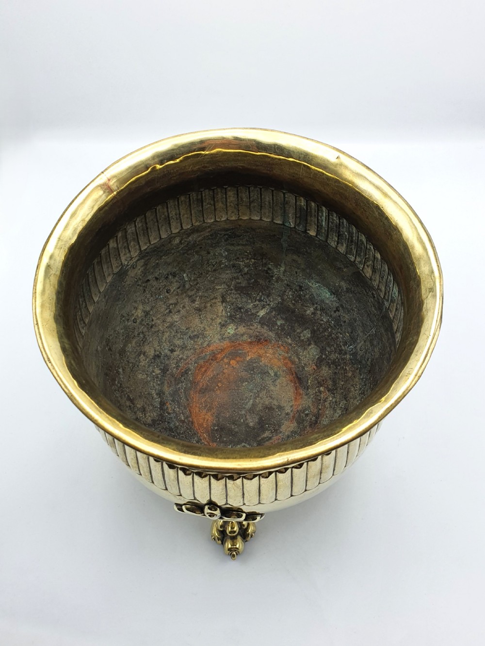 A rounded Edwardian brass jardiniere with a flared rim, a reeded central band, and three decorative cast feet. View IV