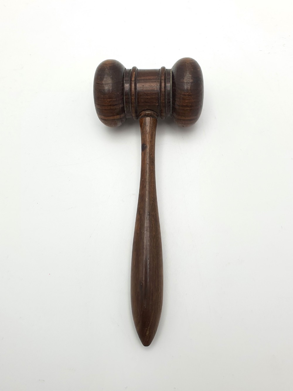 A dark turned hardwood auctioneer gavel featuring a double-ended head with moulded ring details and a tapered handle.
