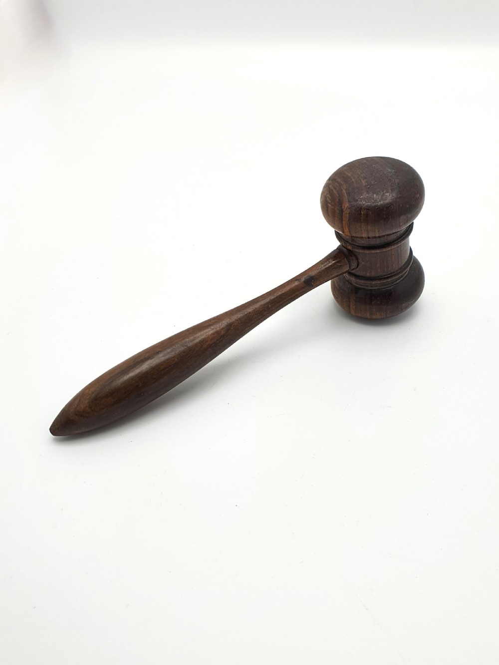 A dark turned hardwood auctioneer gavel featuring a double-ended head with moulded ring details and a tapered handle. View II