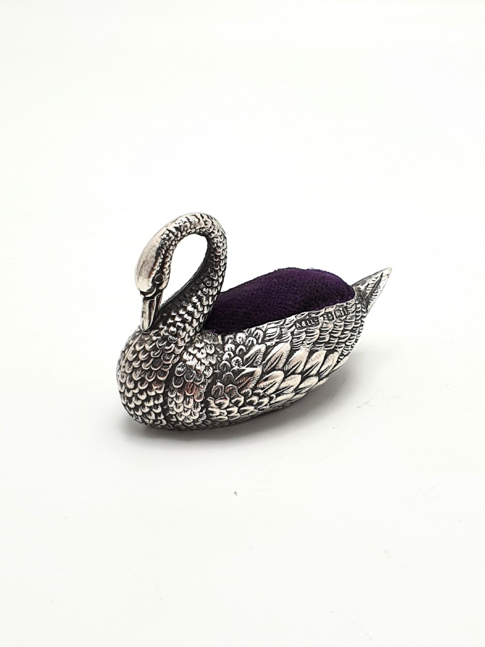A hallmarked Edwardian sterling silver pin cushion crafted in the shape of a swan with detailed feather moulding and a purple velvet insert. View II