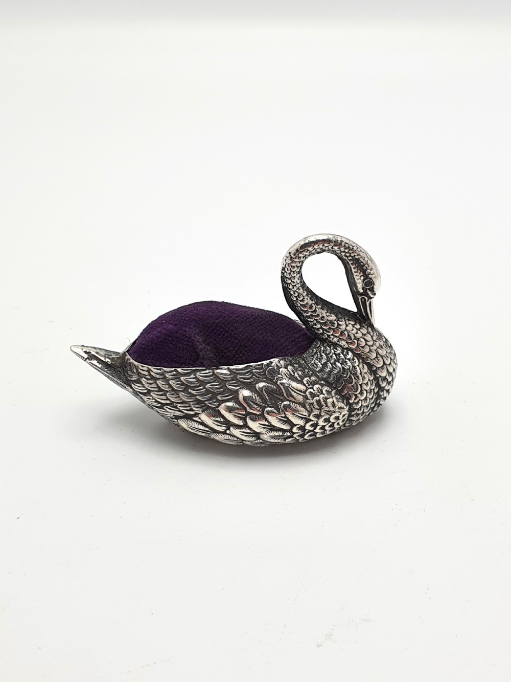 A hallmarked Edwardian sterling silver pin cushion crafted in the shape of a swan with detailed feather moulding and a purple velvet insert. View III