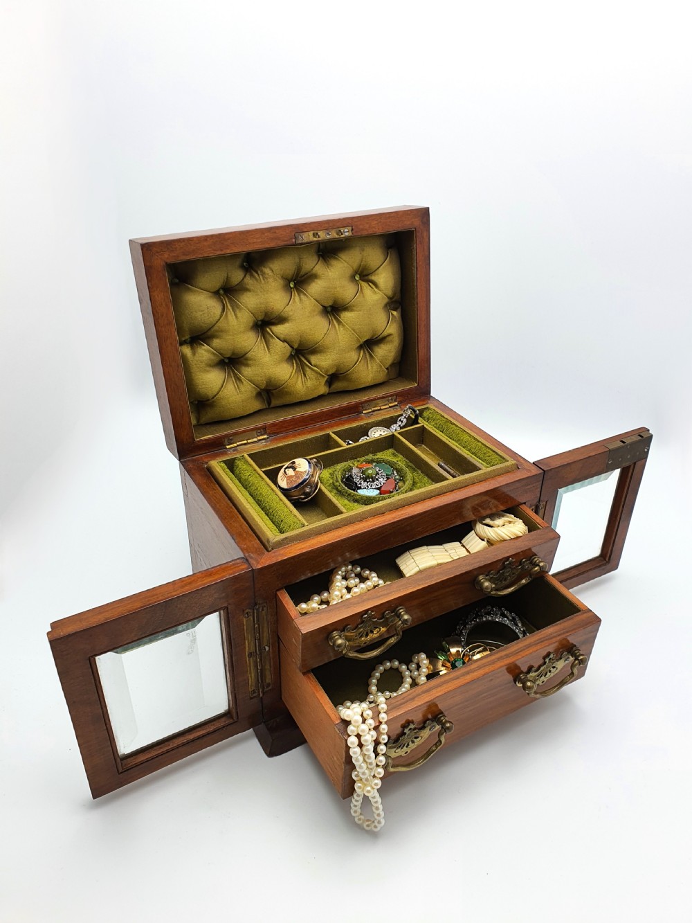 A Victorian walnut jewellery chest with open glass-panelled side doors, two pull-out drawers with brass handles, and an open lid revealing a button-tufted green velvet interior. View II