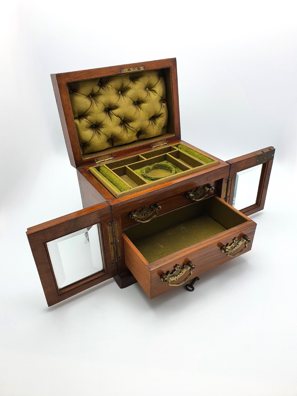 A Victorian walnut jewellery chest with open glass-panelled side doors, two pull-out drawers with brass handles, and an open lid revealing a button-tufted green velvet interior. View VI