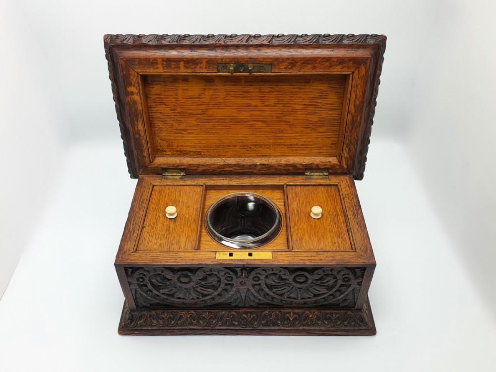 A Victorian dark oak tea caddy featuring detailed relief carvings of cherubs on the lid and carved scrollwork around the sides. View IV