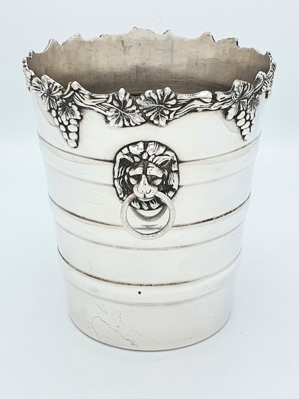A tapered silver-plated wine bucket featuring a scalloped rim decorated with grapevine relief and lion head mask ring handles. View III