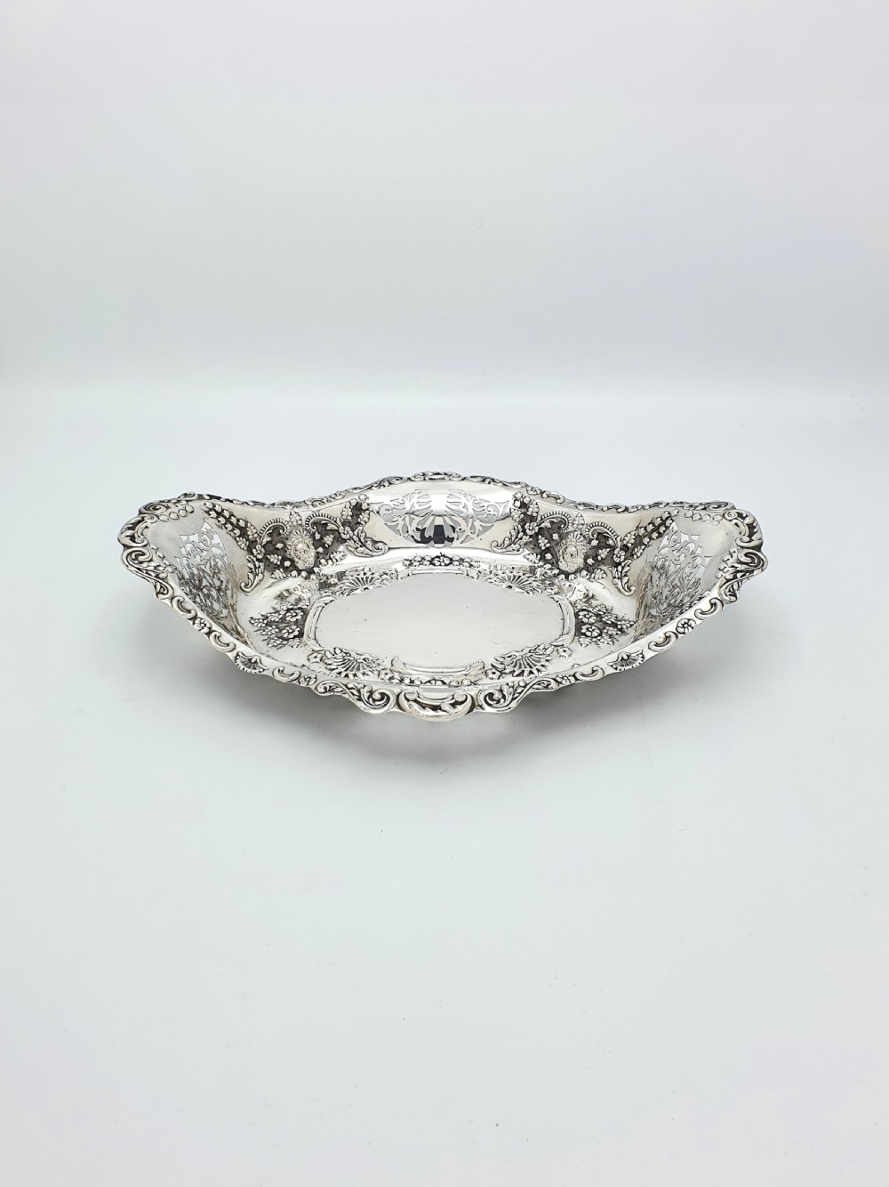 An oval Edwardian solid sterling silver serving dish featuring intricate pierced fretwork sides, scrolled borders, and relief floral decoration. View V
