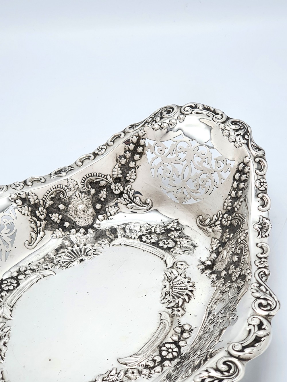 An oval Edwardian solid sterling silver serving dish featuring intricate pierced fretwork sides, scrolled borders, and relief floral decoration. View VI