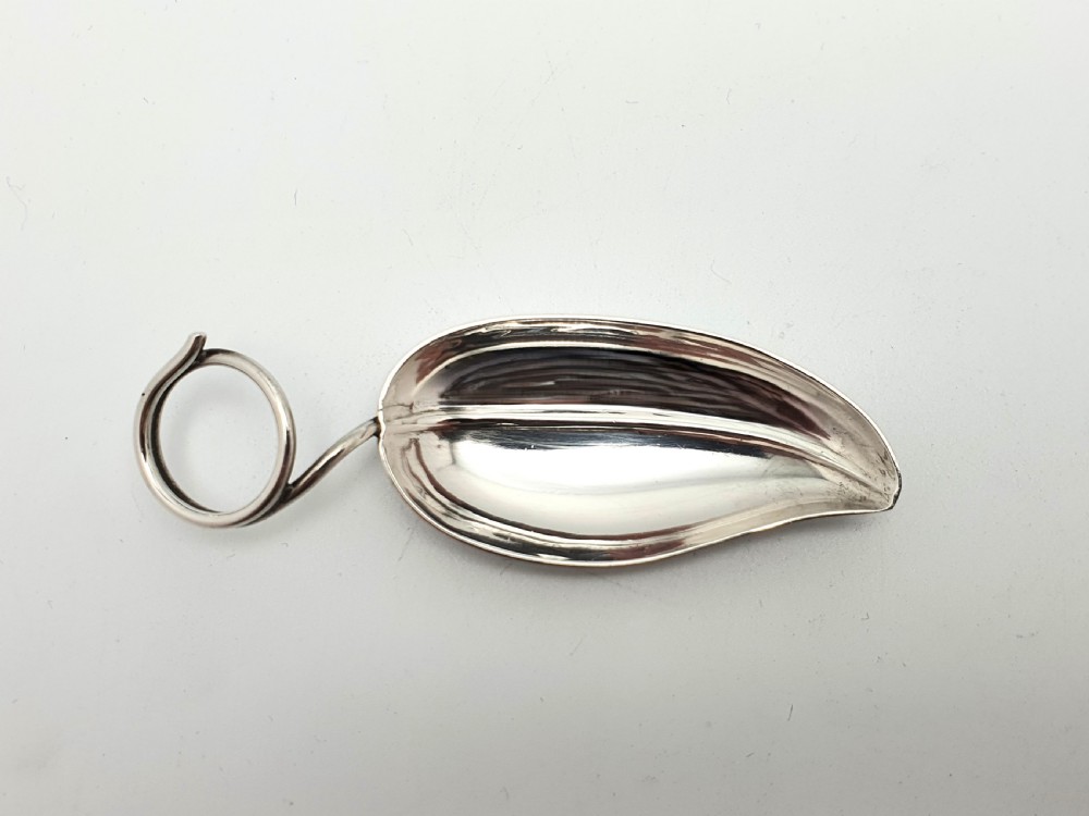 An antique sterling silver tea caddy spoon crafted in the shape of a natural leaf with a wire stem loop handle. View II