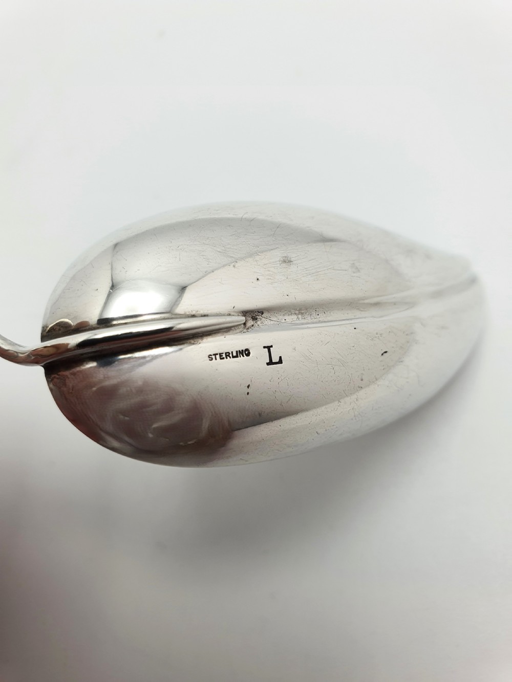 An antique sterling silver tea caddy spoon crafted in the shape of a natural leaf with a wire stem loop handle. View IV