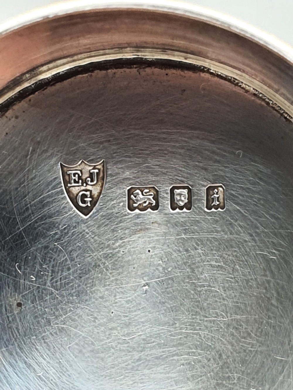 An oval sterling silver tea caddy with a cylindrical push-on cap, engraved leaf borders, and London hallmarks stamped on the front. View V