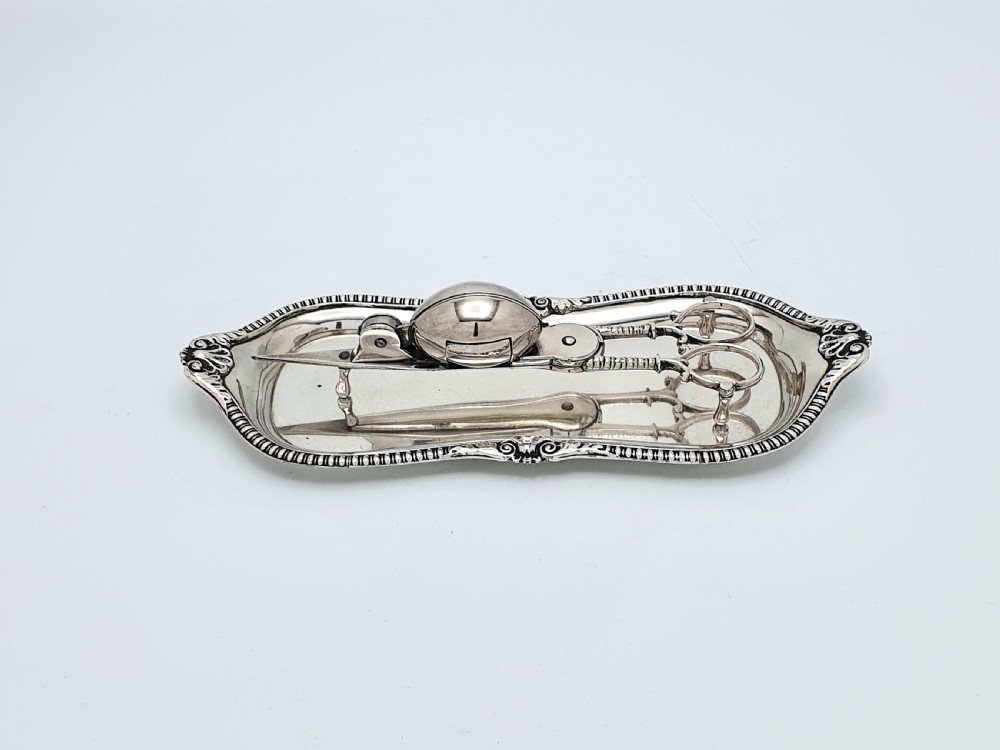 A Victorian silver-plated candle snuffer with scissor trimmers resting on an elongated tray with gadrooned borders.