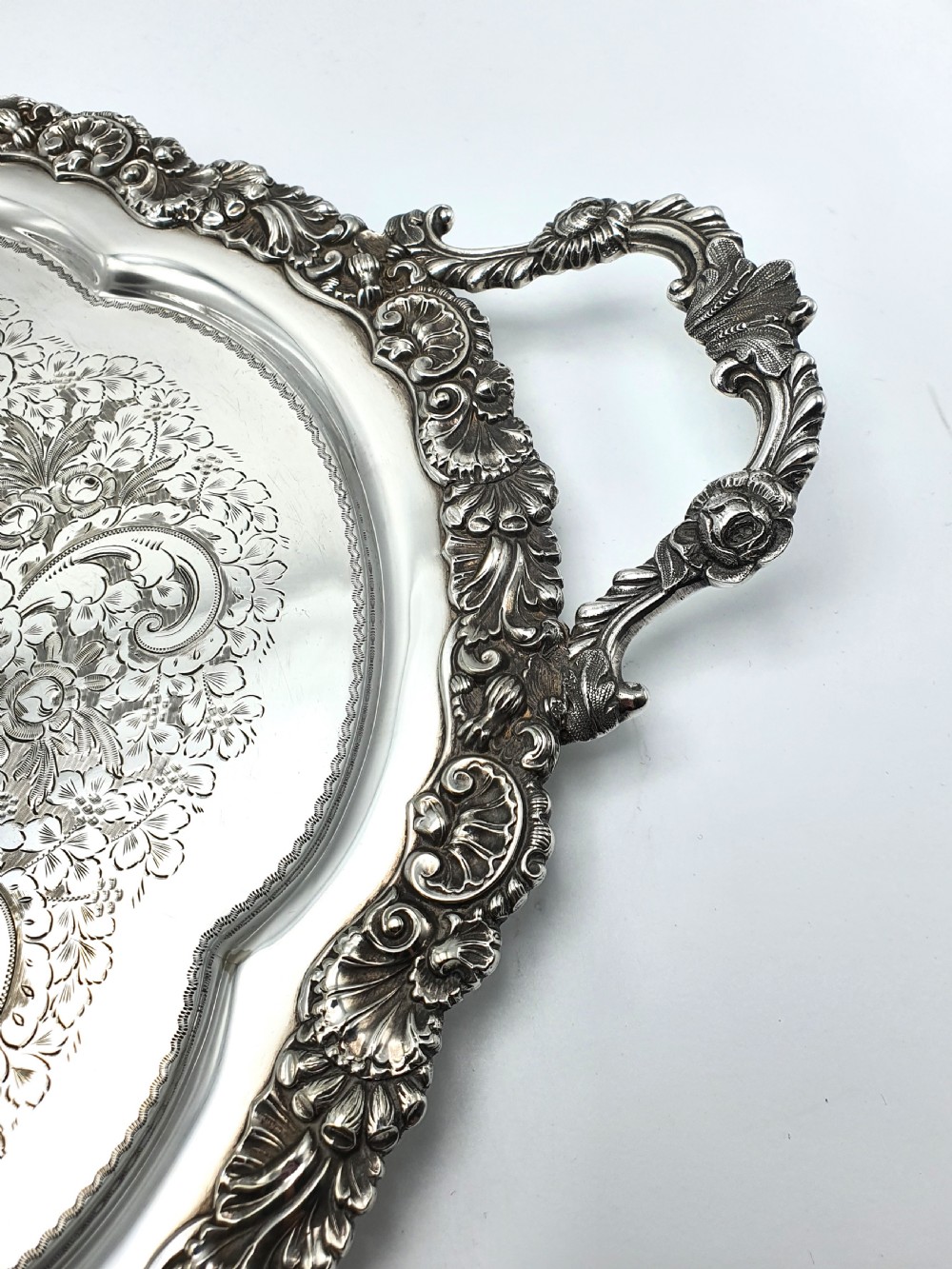 An ornate oval late Victorian silver serving tray featuring twin handles, an intricate hand-engraved scrollwork centre, and a cast shell border. View II