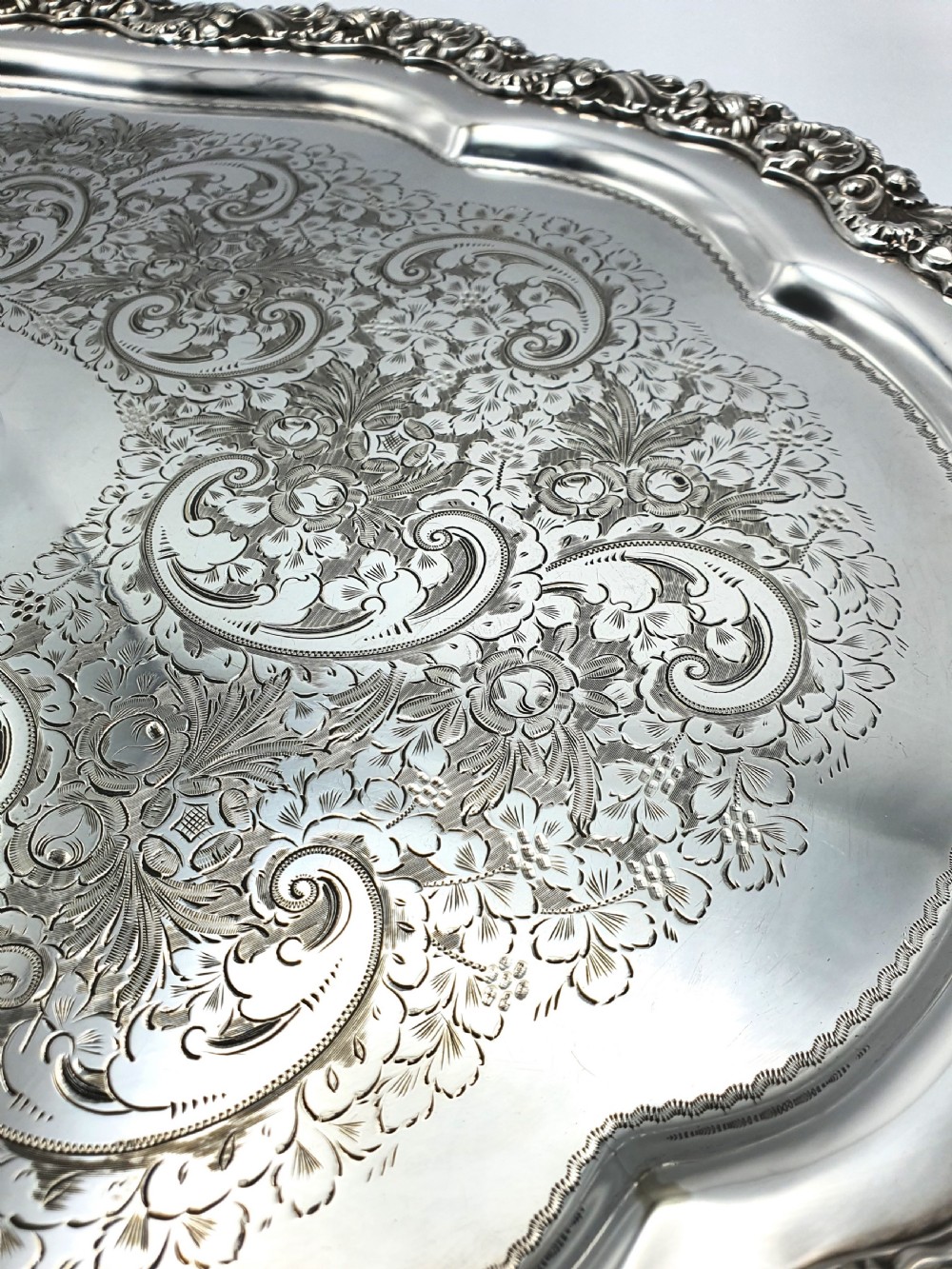 An ornate oval late Victorian silver serving tray featuring twin handles, an intricate hand-engraved scrollwork centre, and a cast shell border. View III