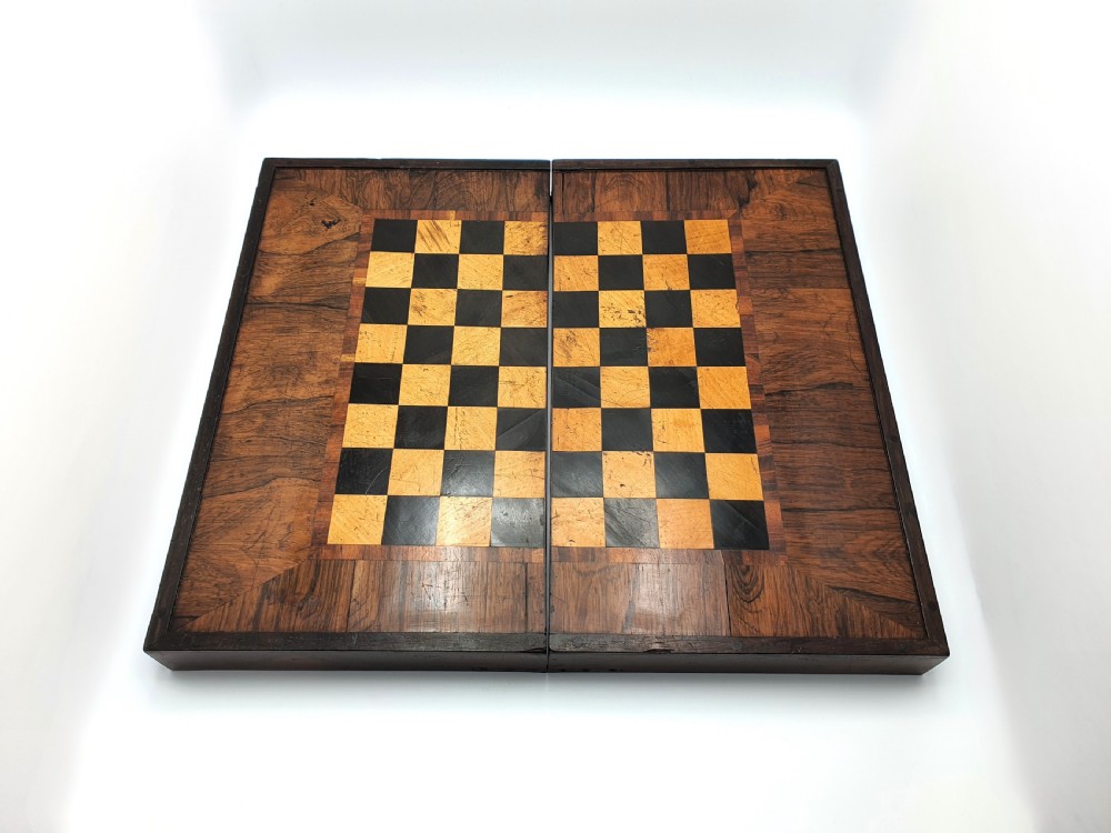A Victorian folding wooden games box featuring a hand-inlaid checkered chessboard surface surrounded by figured timber borders.