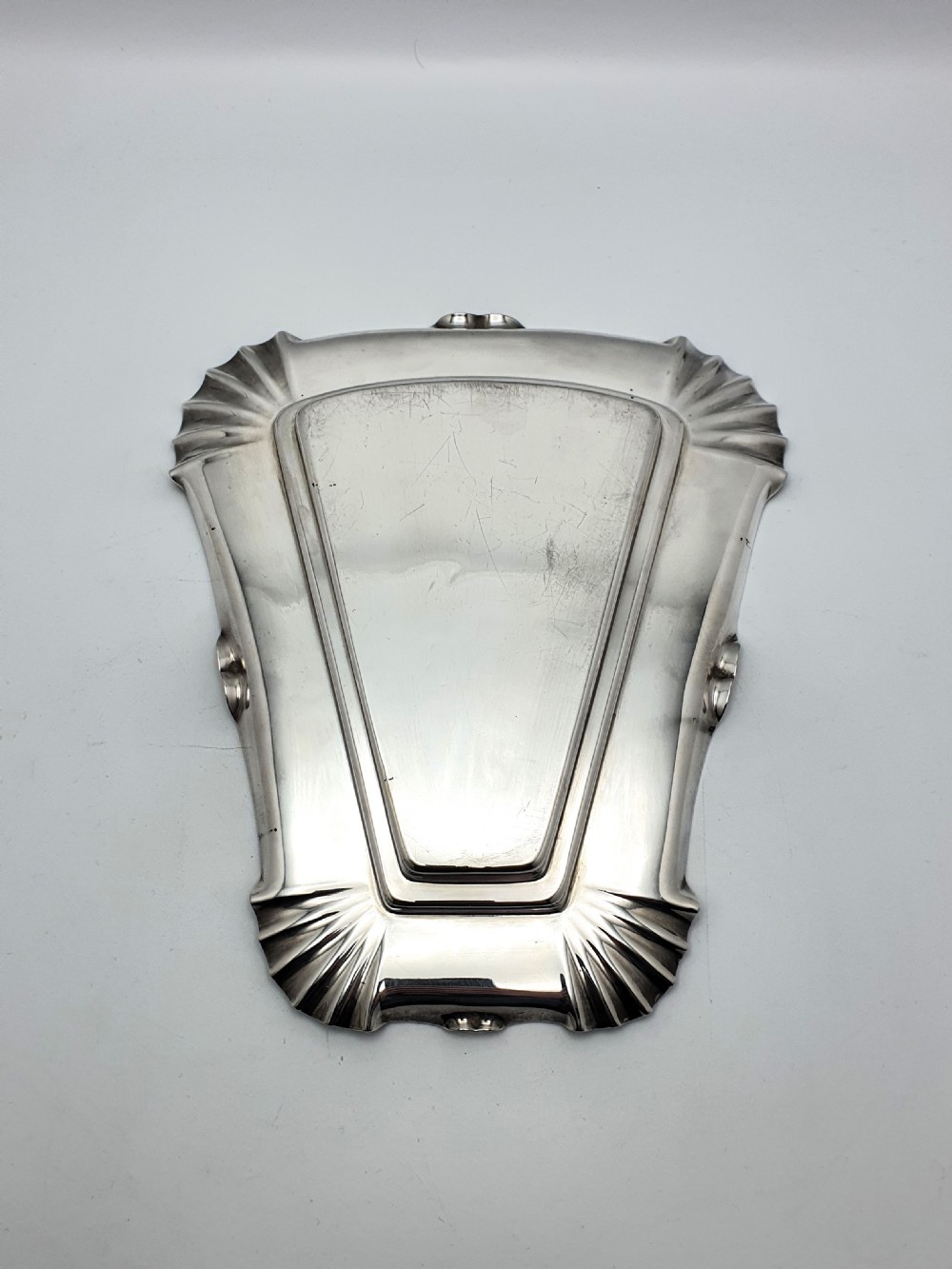 A wedge-shaped glass cheese dome with etched botanical details resting on a contoured silver-plated tray. View X
