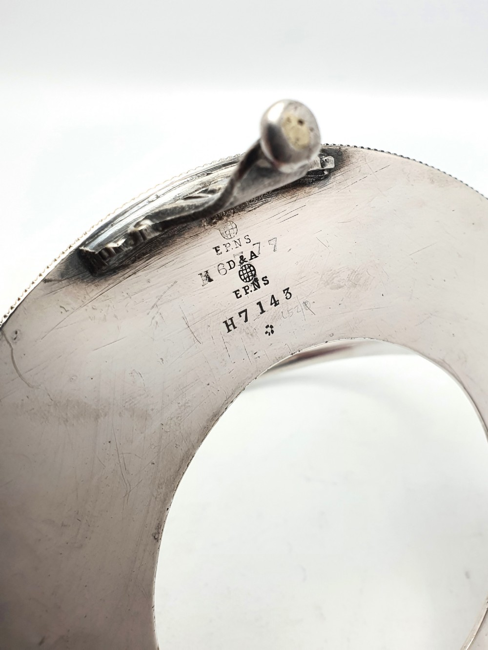 An Edwardian cranberry glass dish resting inside an engraved silver-plated stand with a swing handle and spoon. View X