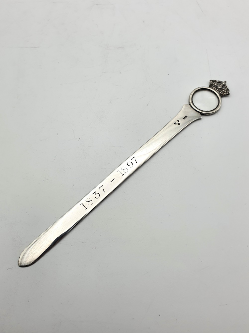 A solid silver Victorian letter opener featuring an engraved ruler edge, makers inscription, and a crown-topped circular finial. View II