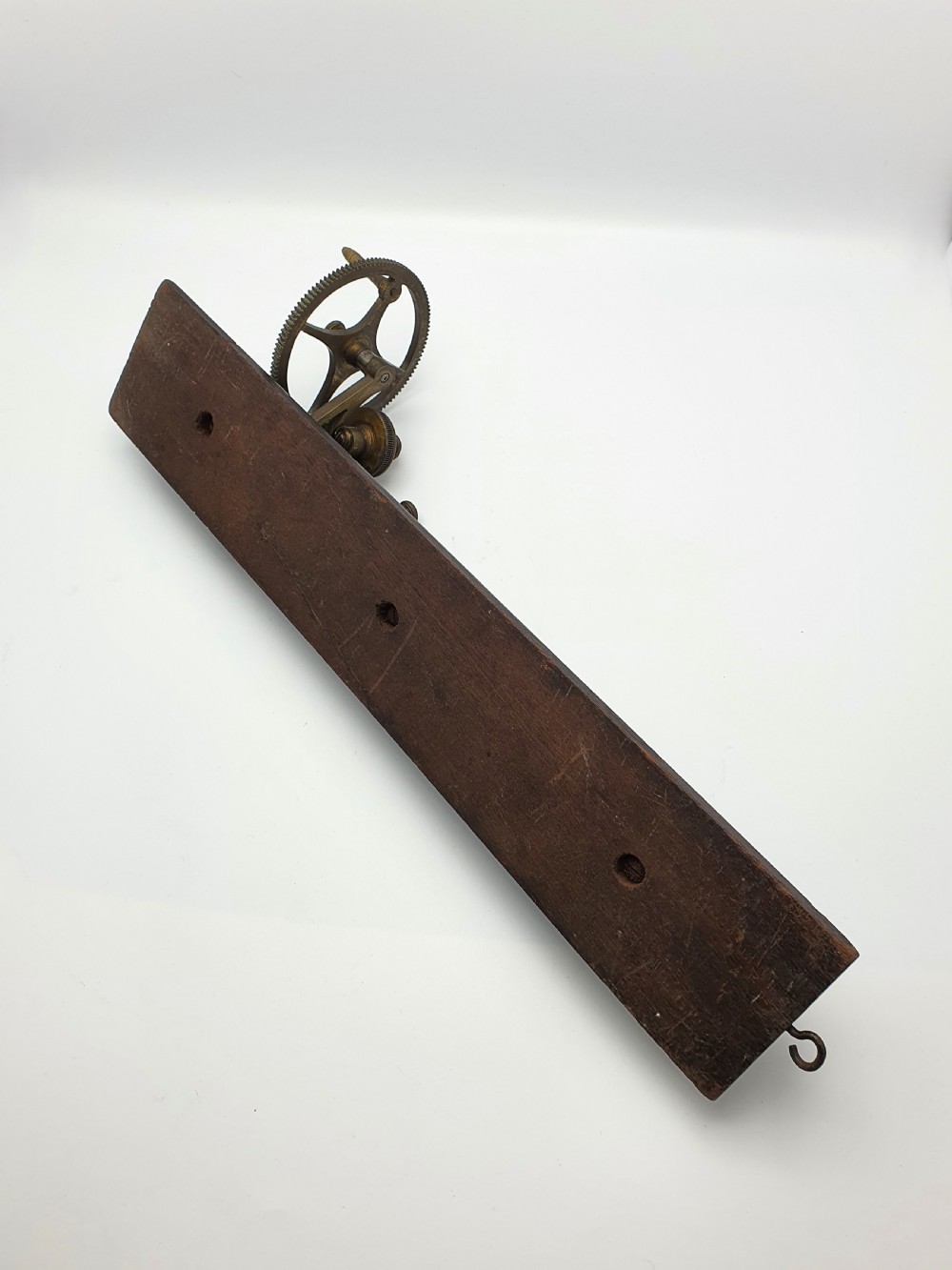 An antique brass thread tester mounted on a dark mahogany base with an engraved ruler scale and geared mechanism. View VIII