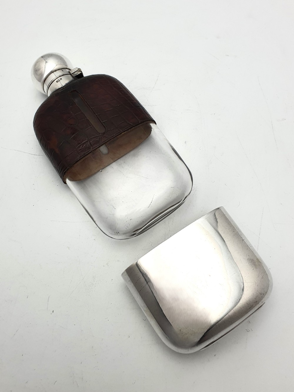 An antique 1920s silver-plated hip flask featuring a dark brown crocodile-embossed leather upper sleeve with a sight window and a silver-plated bayonet cap. View III