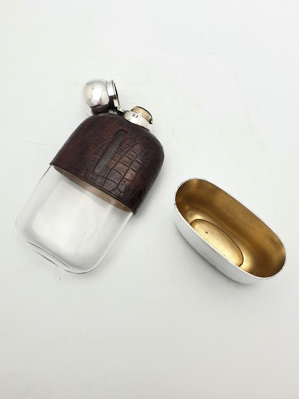 An antique 1920s silver-plated hip flask featuring a dark brown crocodile-embossed leather upper sleeve with a sight window and a silver-plated bayonet cap. View V