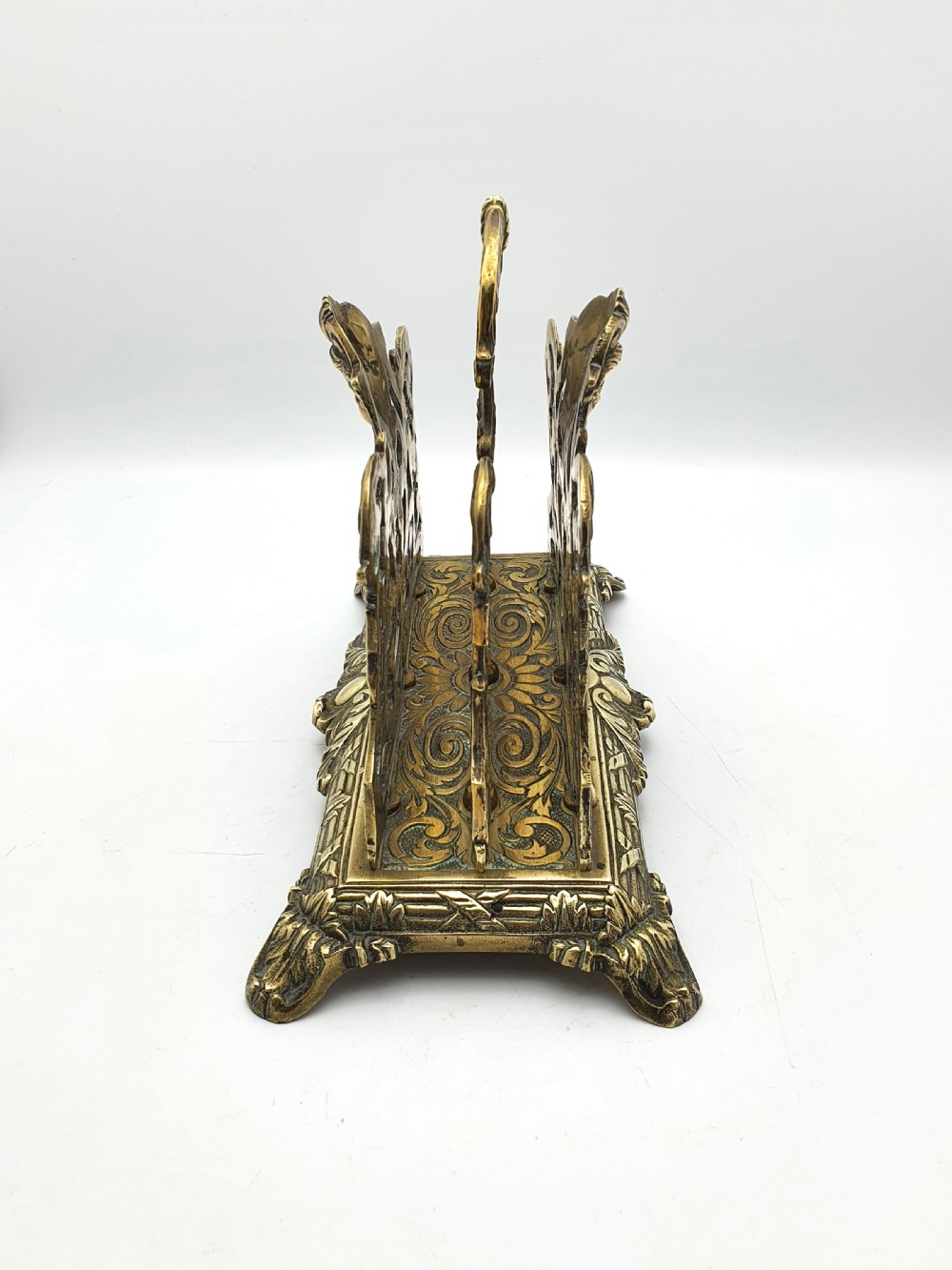 An ornate cast brass letter rack featuring openwork scrollwork, a central cherub face motif, a top handle, and a decorated rectangular base. View II