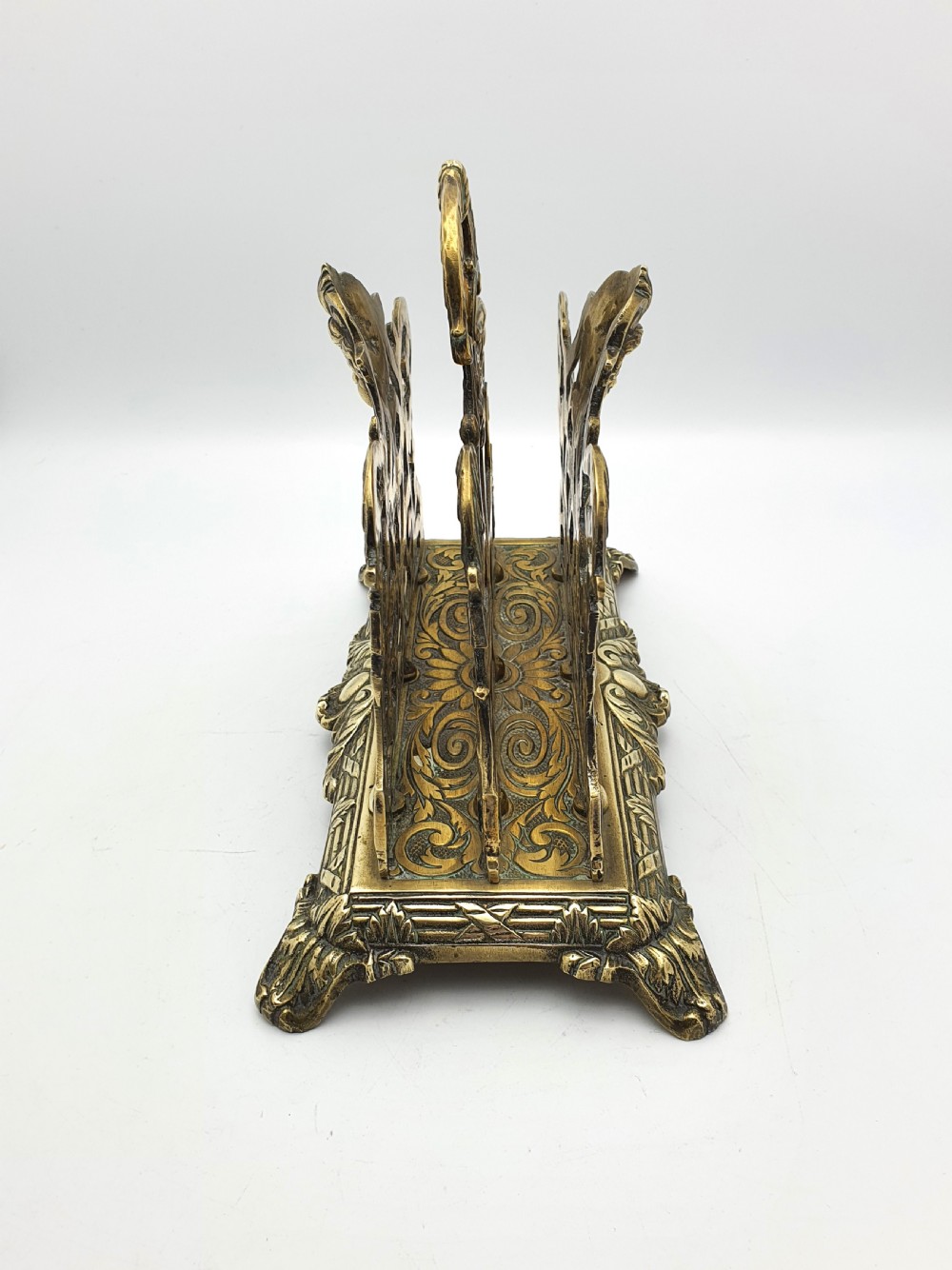 An ornate cast brass letter rack featuring openwork scrollwork, a central cherub face motif, a top handle, and a decorated rectangular base. View IV