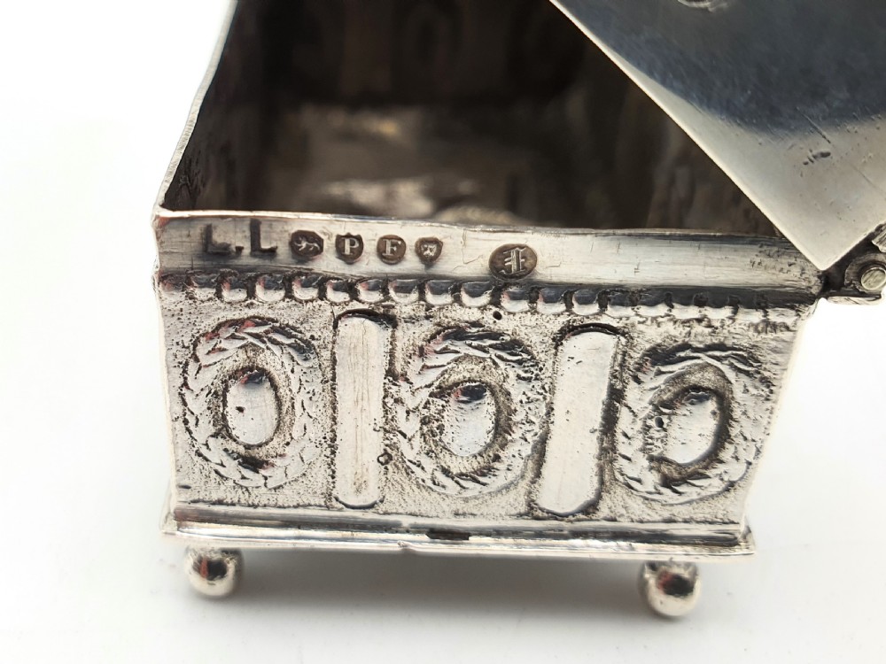 An embossed silver rectangular trinket box featuring a domed lid decorated with figures in relief and supported by four small ball feet. View XXII