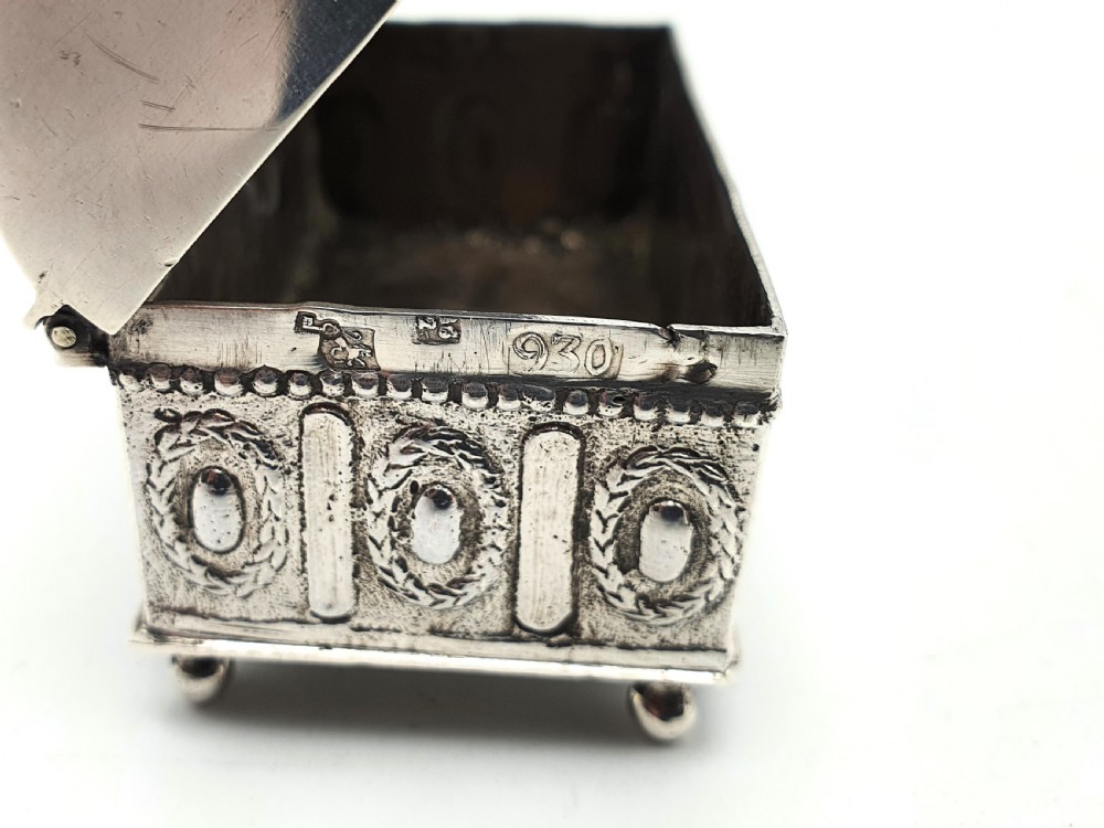 An embossed silver rectangular trinket box featuring a domed lid decorated with figures in relief and supported by four small ball feet. View XXIII