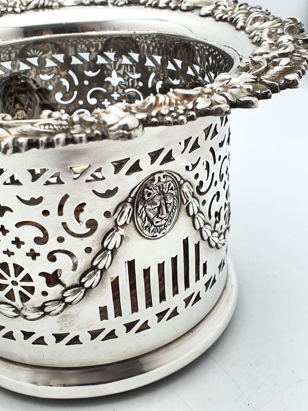 A pair of circular silver-plated wine coasters with pierced fretwork sides, garland swags, medallion motifs, and decorative rims. View V