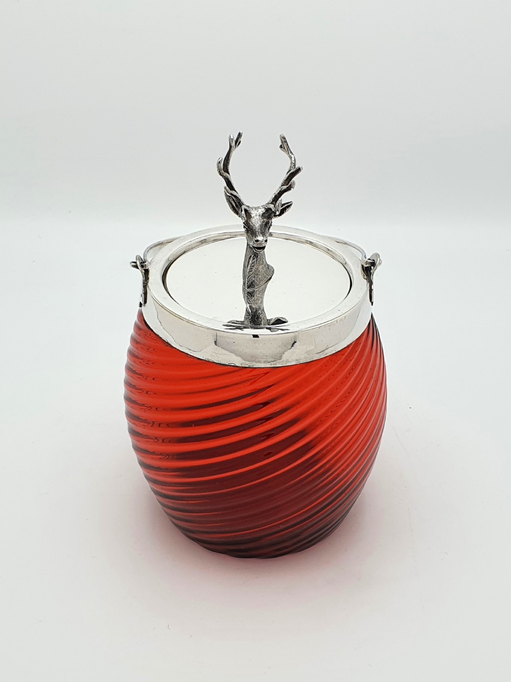 A Victorian ribbed cranberry red glass biscuit barrel featuring a silver-plated rim, handle mounts, and a lid surmounted by a stag head finial. View II