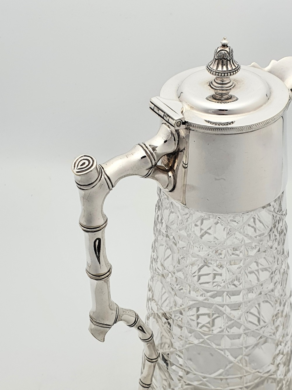 An Edwardian tapered cut glass claret jug with a diamond pattern, silver-plated collar, hinged lid, and a faux-bamboo handle. View III
