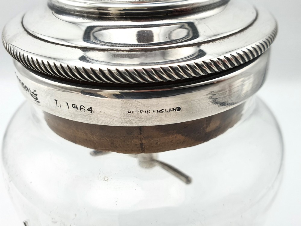 A clear glass cocktail shaker with etched fluid ounce measurement markings, fitted with a cork seal and a polished silver-plated cap. View V