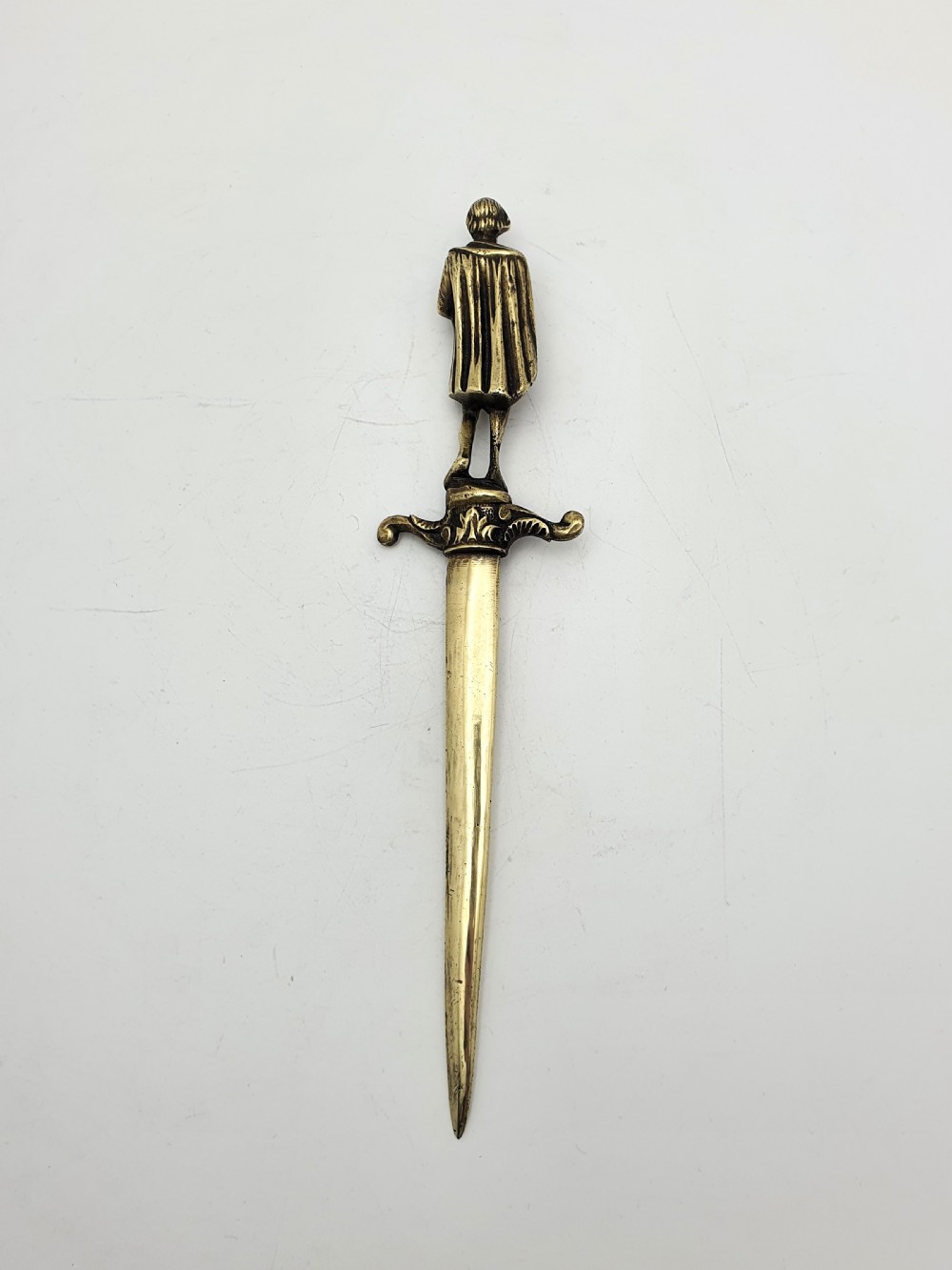 An antique brass letter opener shaped like a dagger featuring a sculpted figure of William Shakespeare on the handle and his name engraved on the blade. View IV