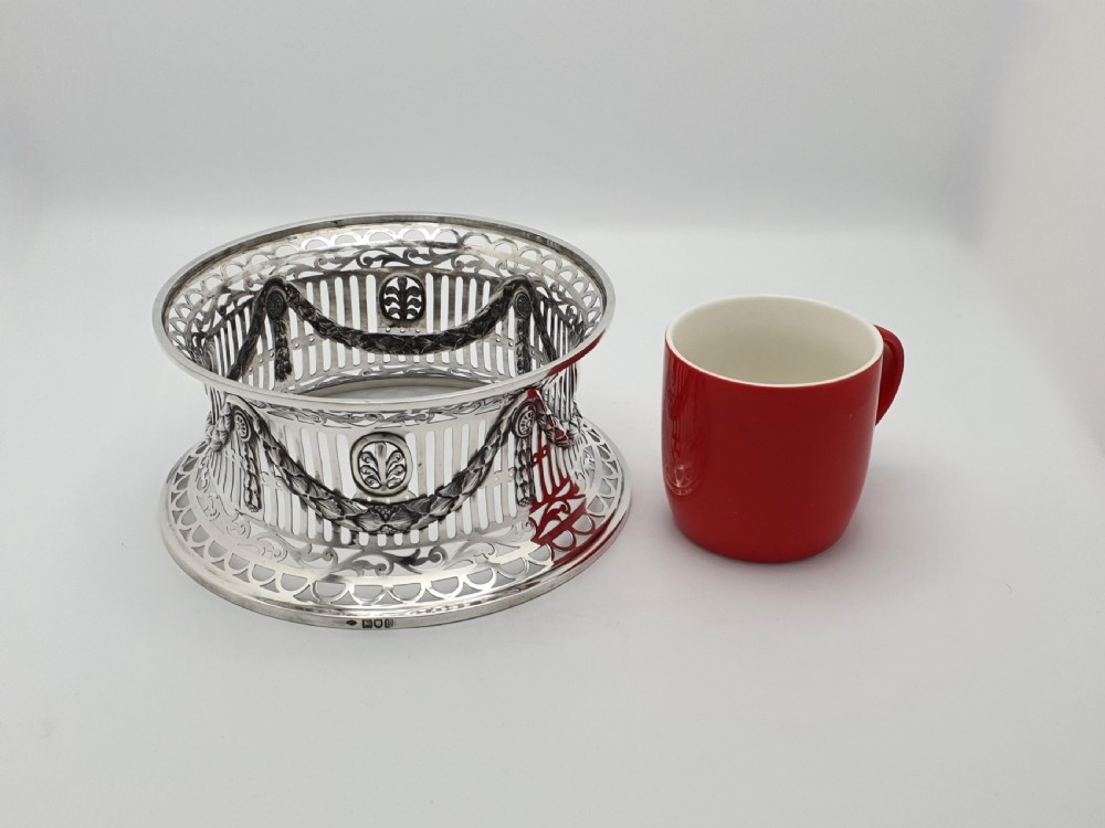 An Edwardian pierced sterling silver dish ring featuring draped swags, vertical slats, oval medallions, and decorative scroll rims on a waisted spool body. View II