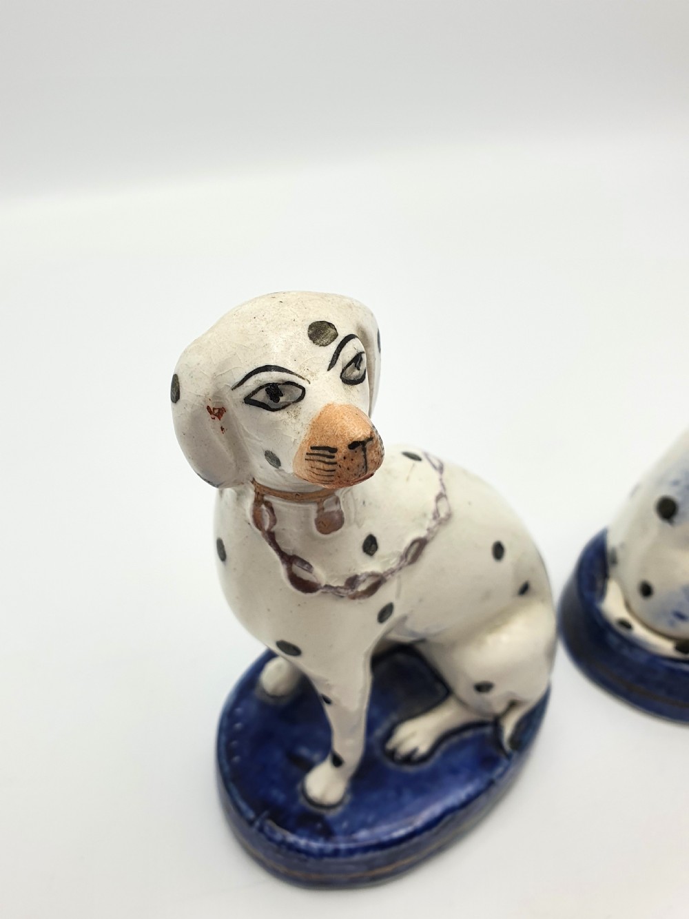 A pair of late Victorian Staffordshire earthenware figures depicting seated Dalmatians with hand-painted black spots on cobalt blue bases. View III