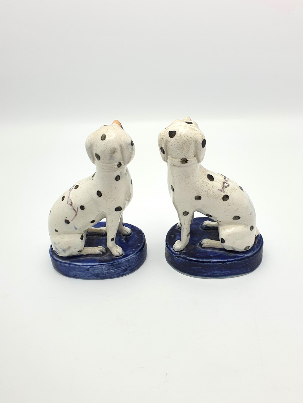 A pair of late Victorian Staffordshire earthenware figures depicting seated Dalmatians with hand-painted black spots on cobalt blue bases. View V