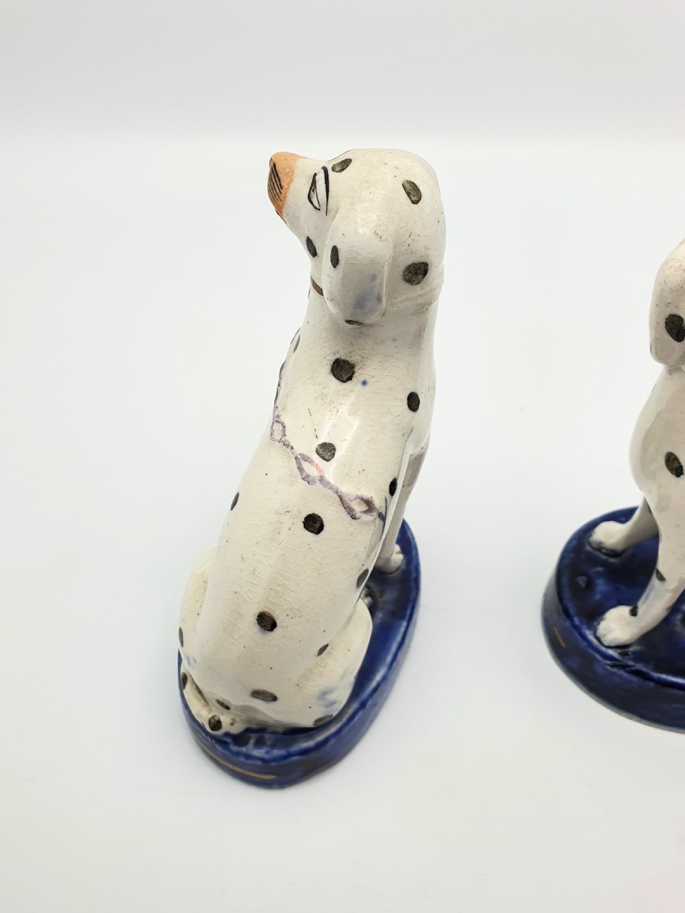 A pair of late Victorian Staffordshire earthenware figures depicting seated Dalmatians with hand-painted black spots on cobalt blue bases. View VI