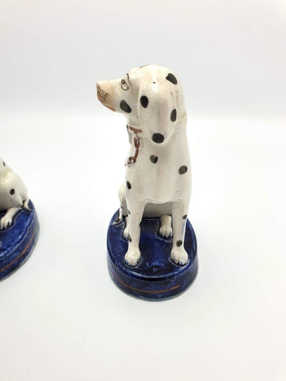 A pair of late Victorian Staffordshire earthenware figures depicting seated Dalmatians with hand-painted black spots on cobalt blue bases. View VIII