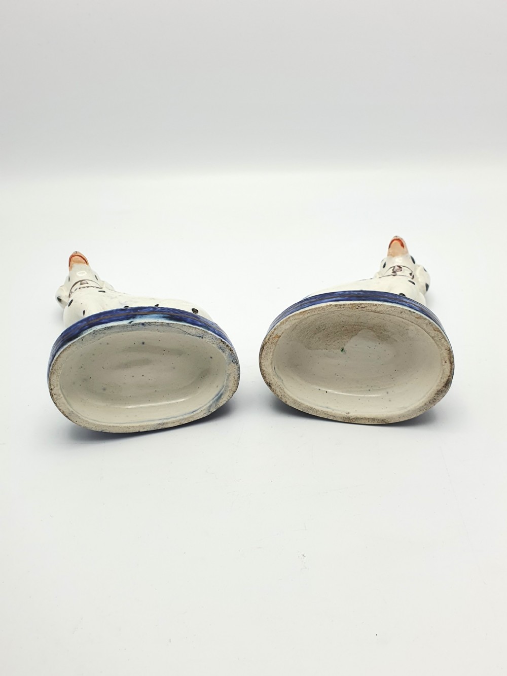 A pair of late Victorian Staffordshire earthenware figures depicting seated Dalmatians with hand-painted black spots on cobalt blue bases. View IX
