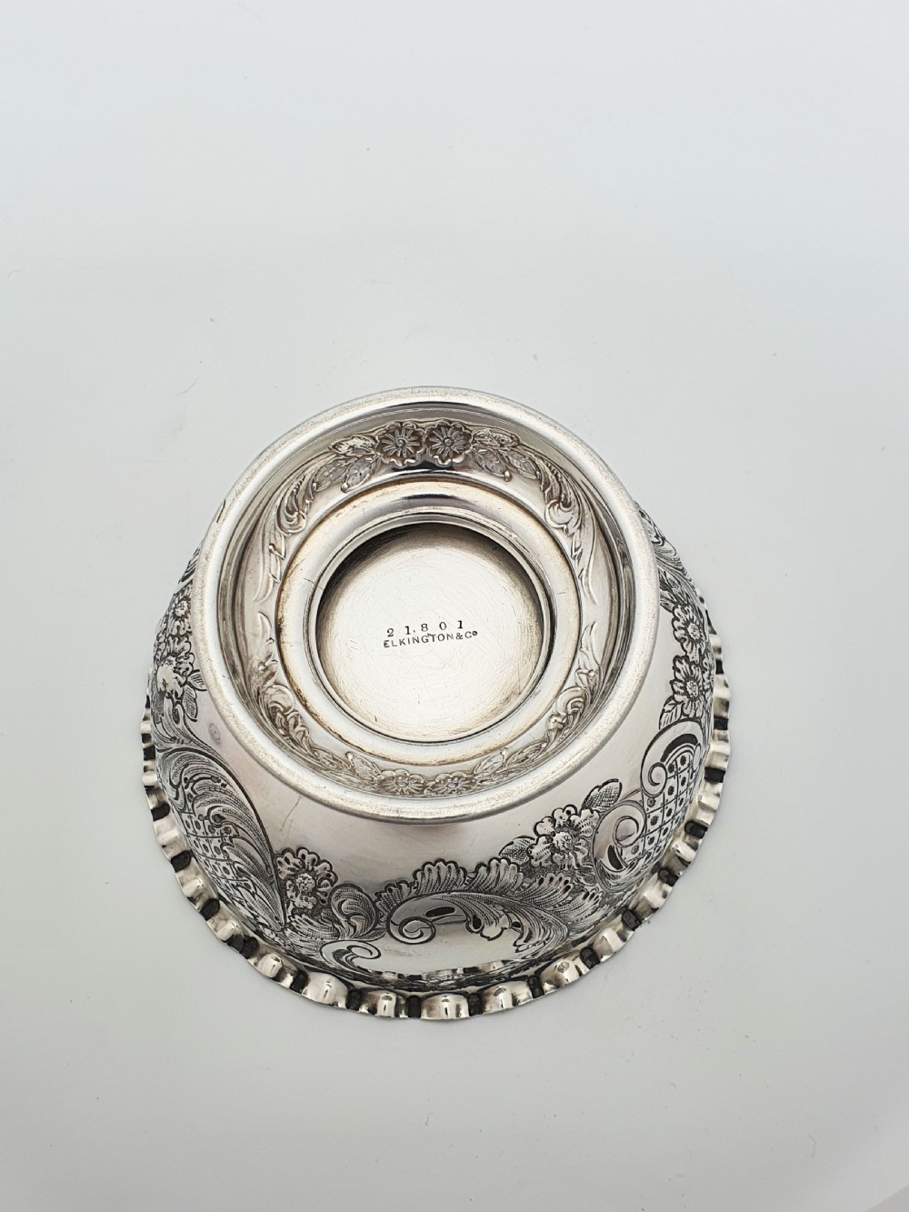 A circular Victorian sterling silver bowl featuring ornate repousse floral chasing, a crimped fluted rim, and a raised pedestal foot. View VIII
