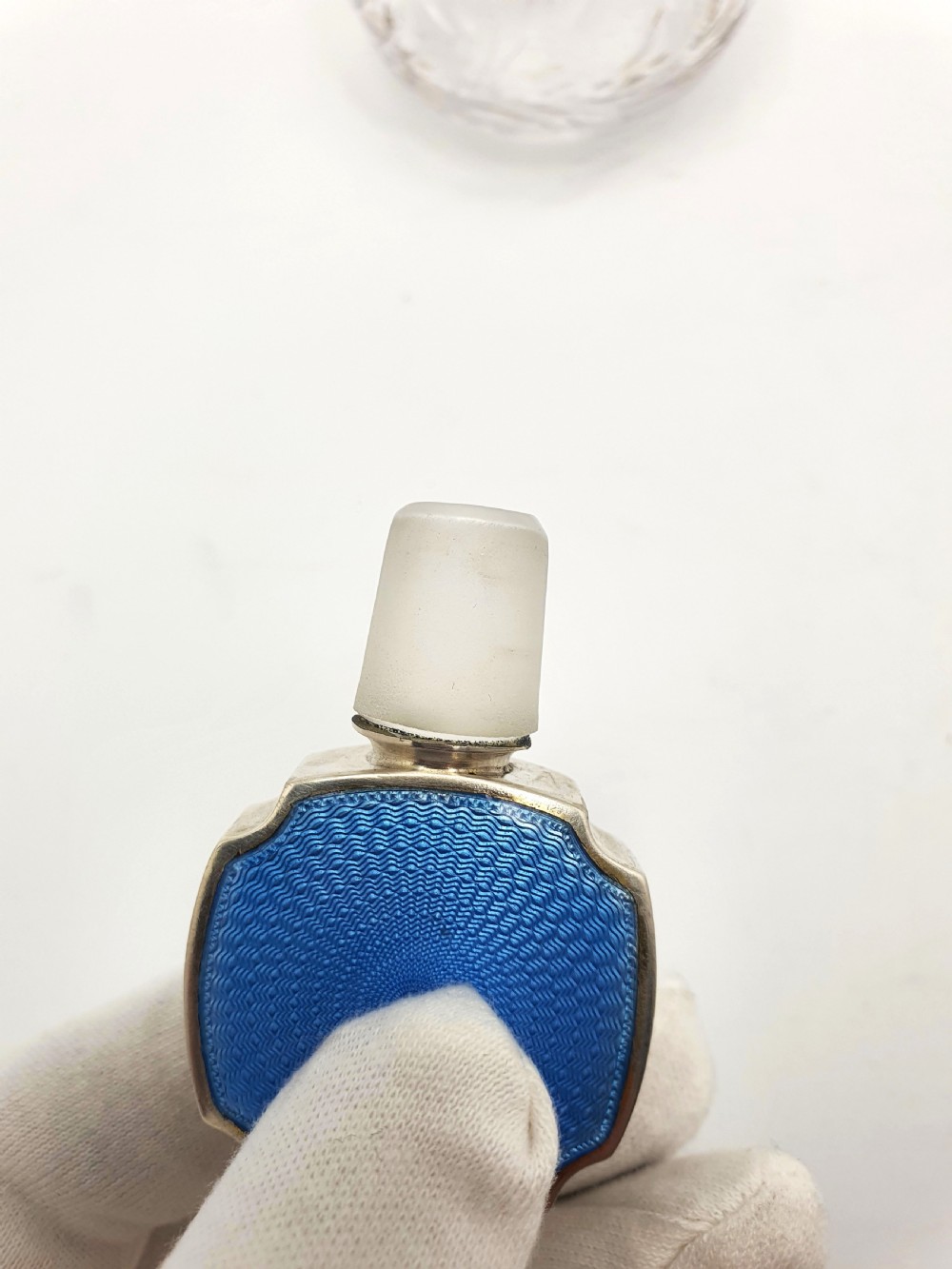 A clear cut glass scent bottle featuring a bright blue guilloche enamel collar and matching octagonal stopper set in sterling silver. View VIII