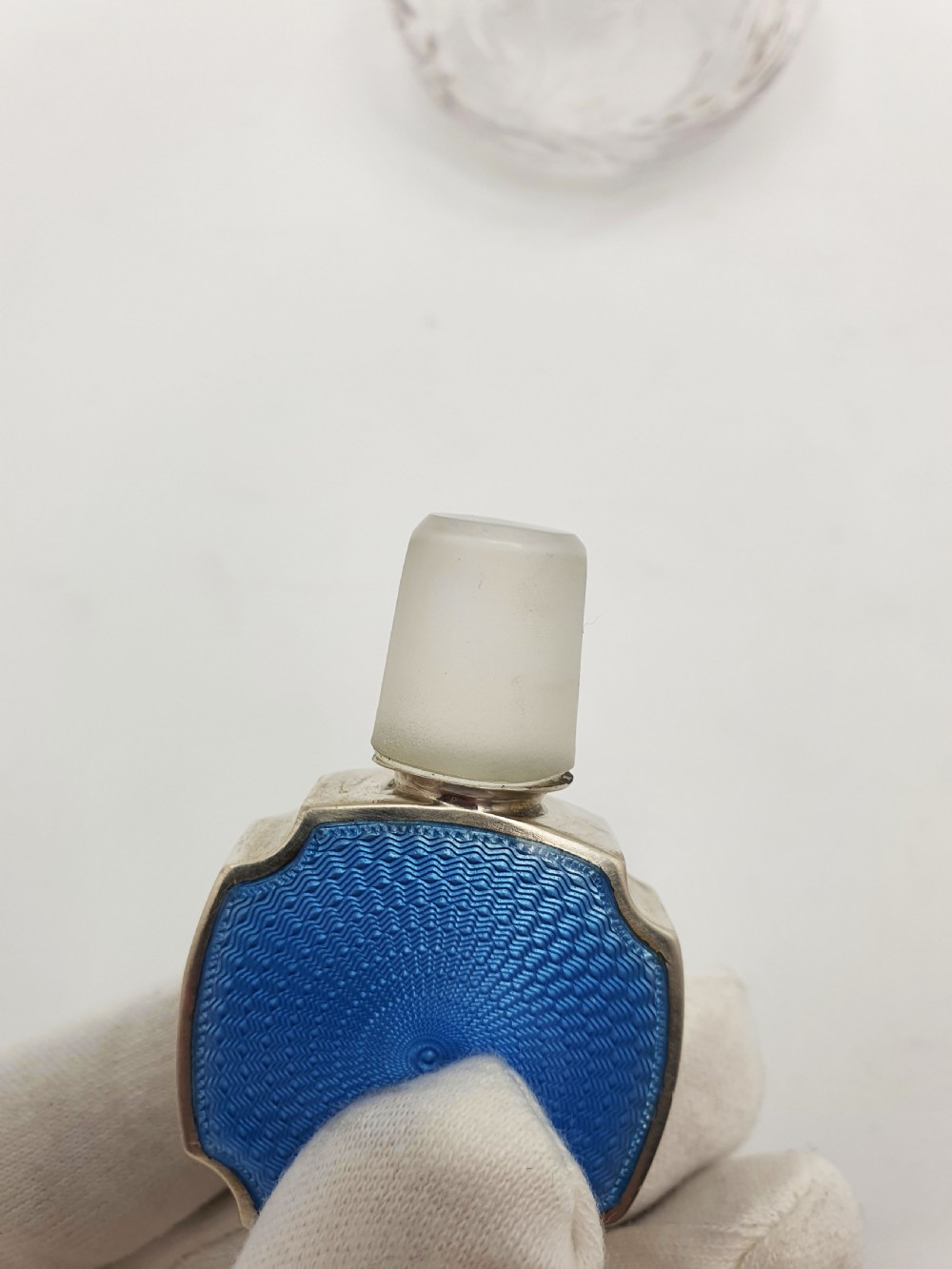 A clear cut glass scent bottle featuring a bright blue guilloche enamel collar and matching octagonal stopper set in sterling silver. View IX