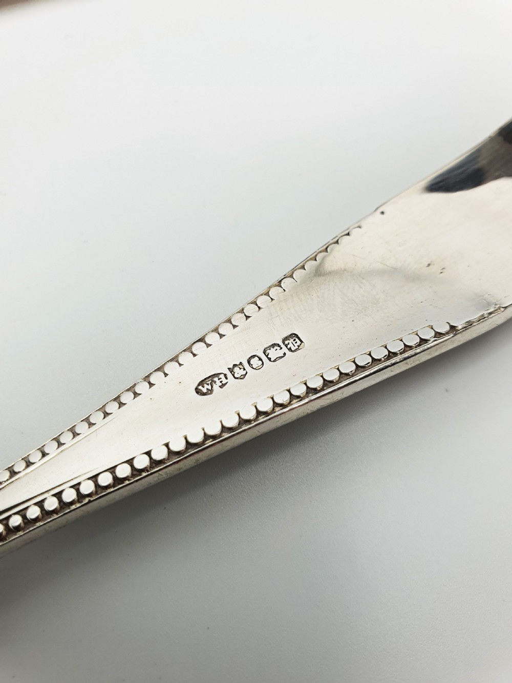Antique silver-plated serving tongs featuring decorative pierced ends and a beaded edge handle design. View VII
