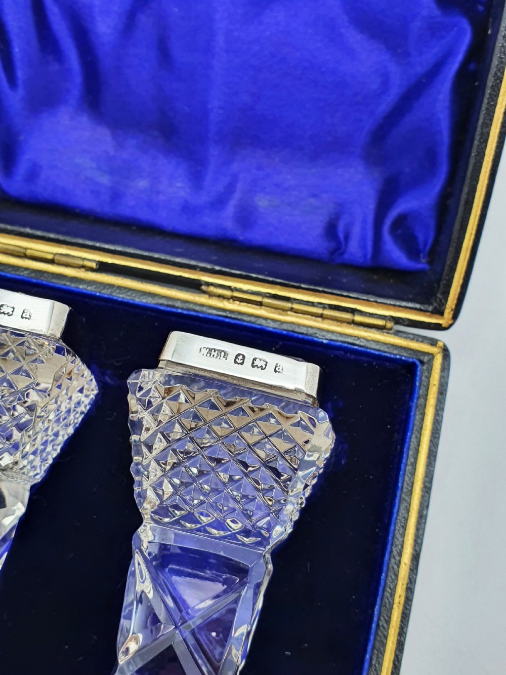 A pair of cut glass knife rests with hallmarked silver end caps housed in a dark blue velvet-lined fitted presentation case. View II