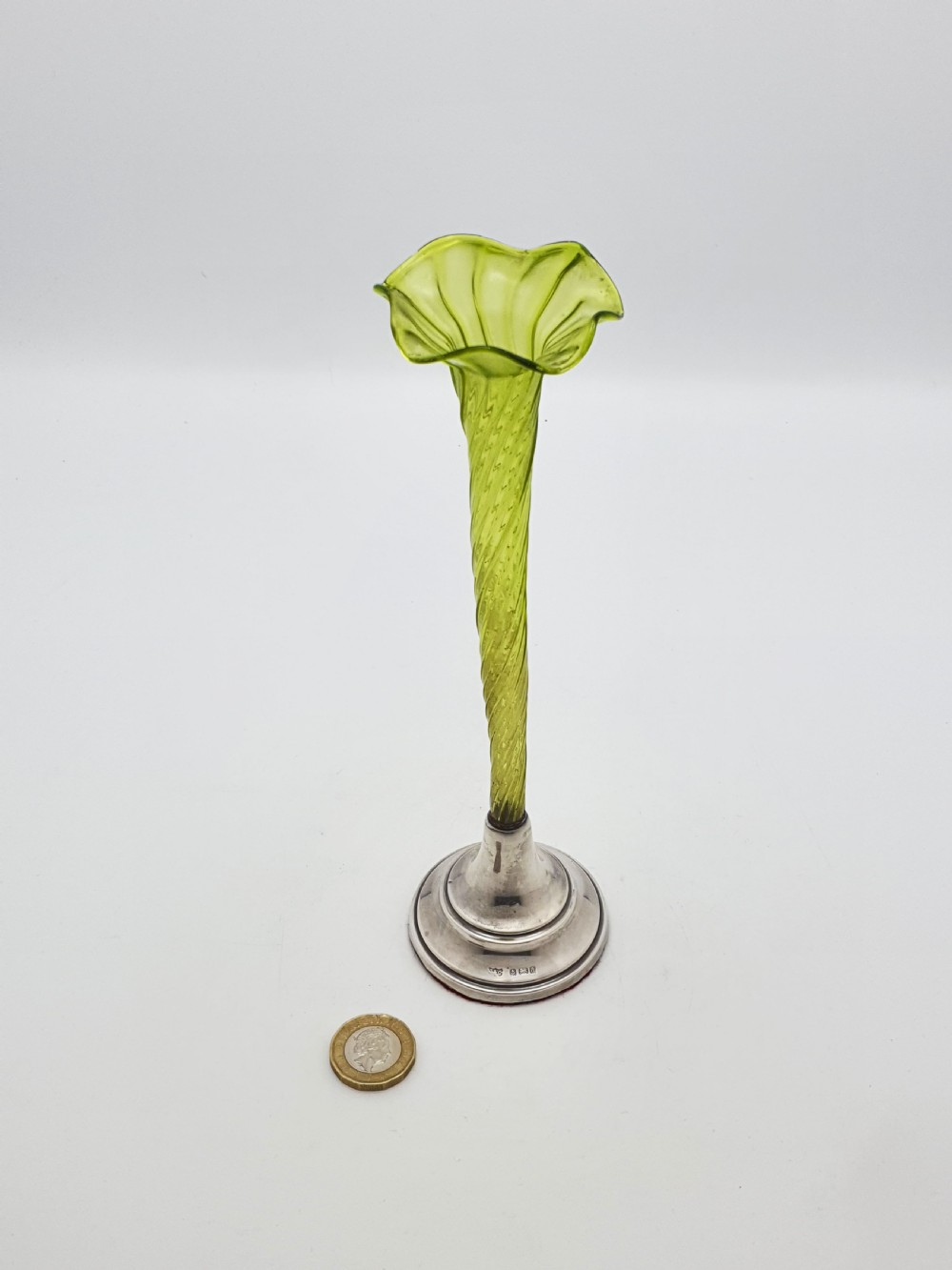 An Edwardian green glass bud vase with a spiral stem and frilled rim, set into a circular hallmarked sterling silver base. View VI
