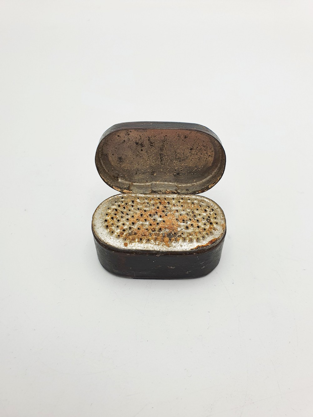 An open oval Georgian metal pocket nutmeg grater showing a hinged lid and a perforated grating surface with age patina.