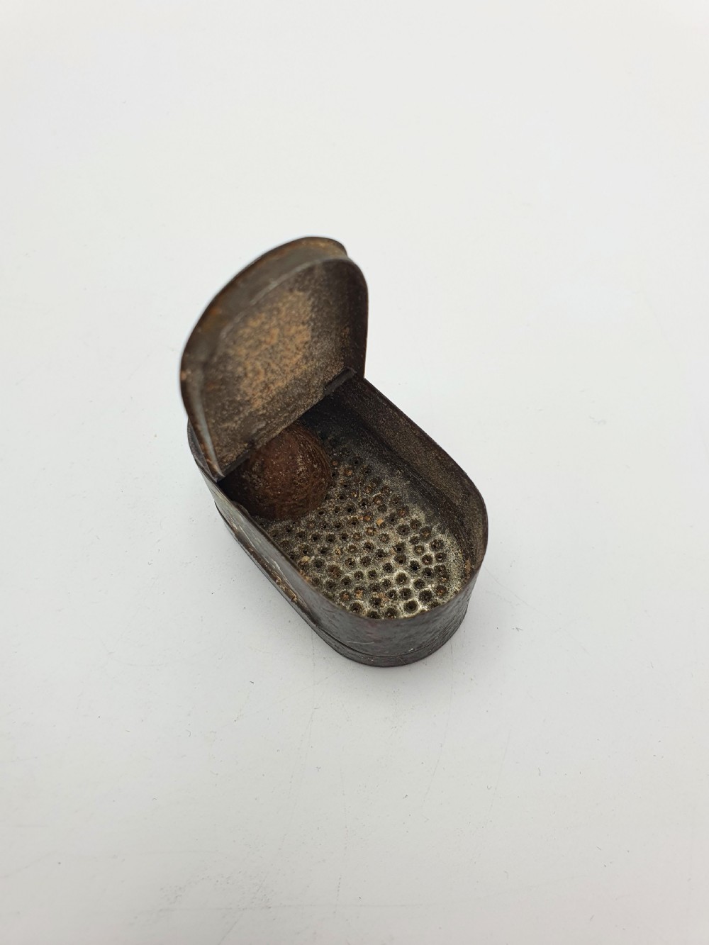 An open oval Georgian metal pocket nutmeg grater showing a hinged lid and a perforated grating surface with age patina. View III