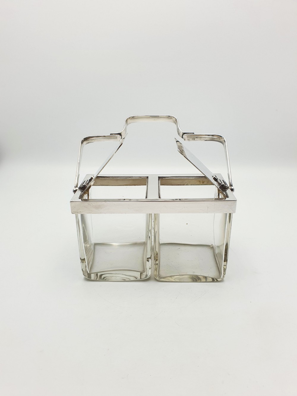 An antique silver-plated metal stand holding two clear rectangular glass jars with a central handle and mechanical lid system.