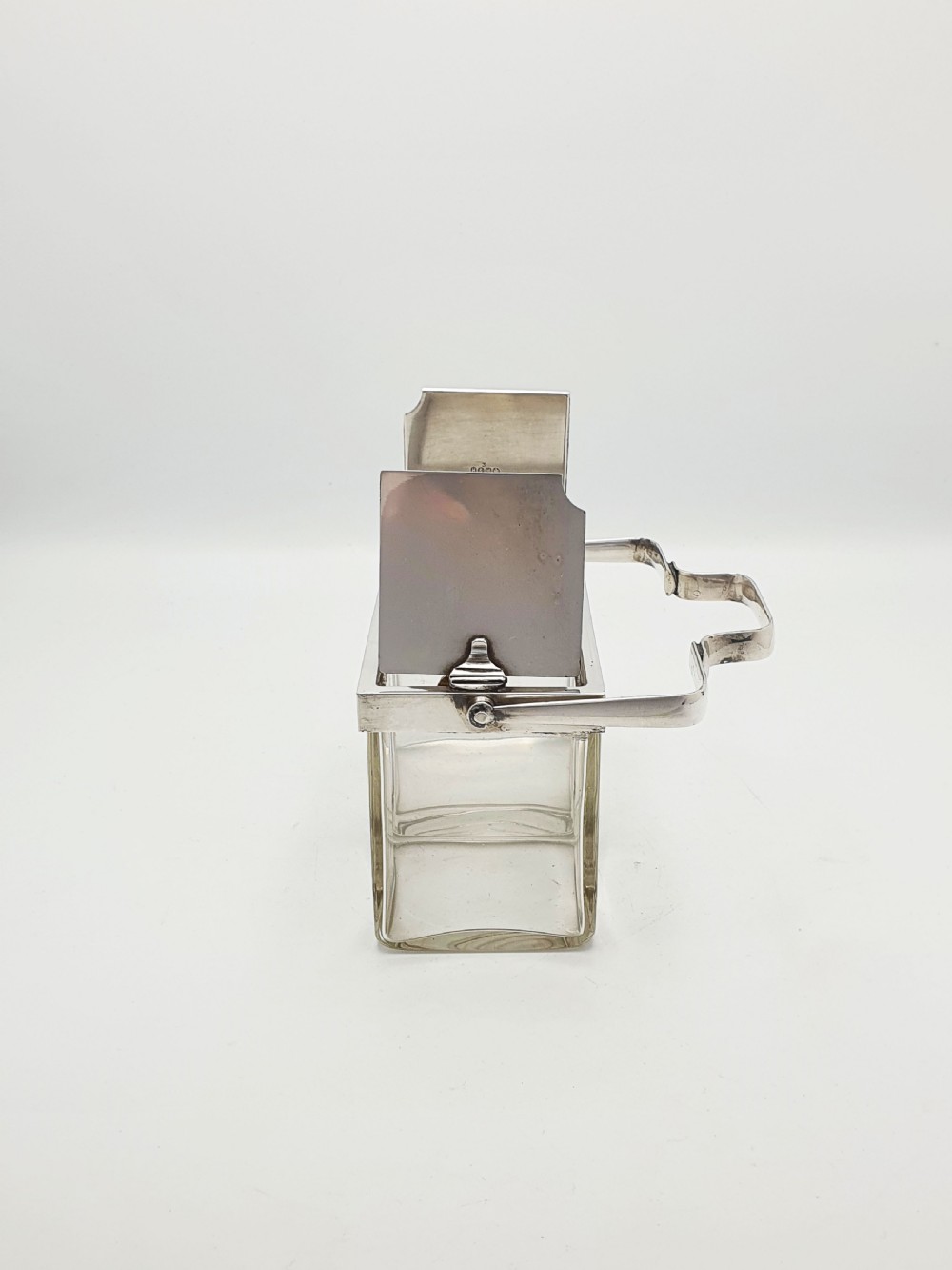 An antique silver-plated metal stand holding two clear rectangular glass jars with a central handle and mechanical lid system. View VII
