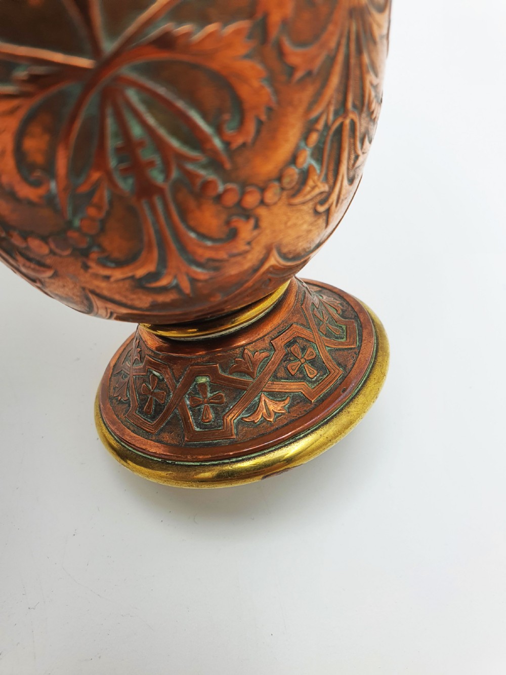 A pair of antique French copper urns featuring brass rims, pedestal bases, and chased floral motifs. View III